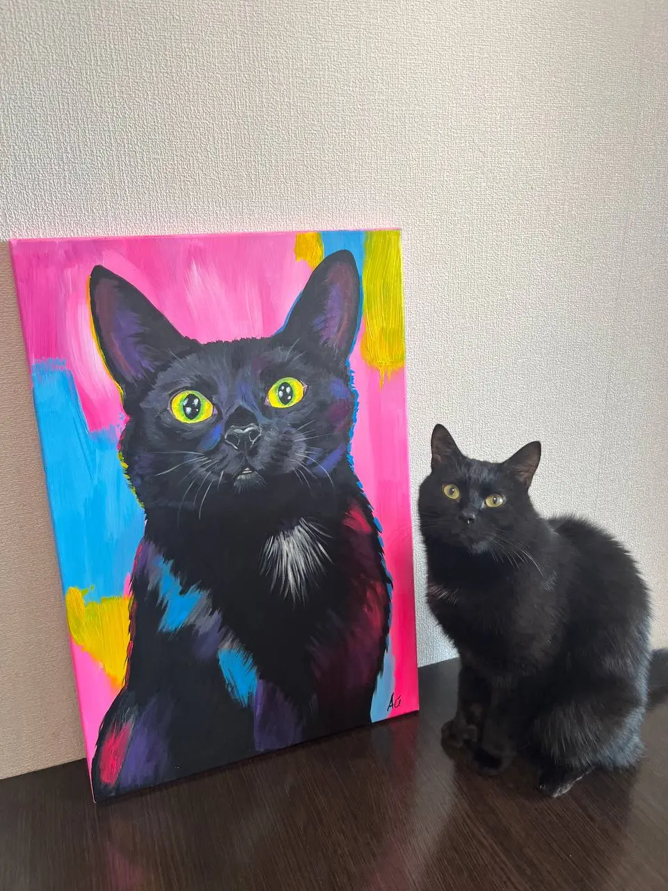 Чёрный кот рядом со своим ярким портретом